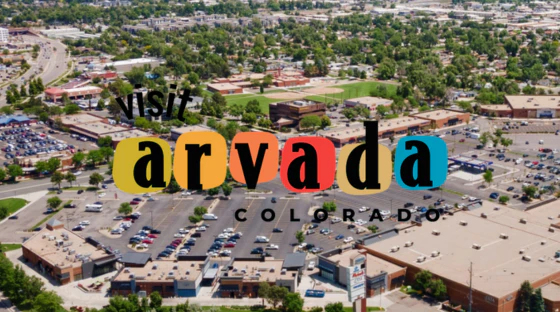 Visit Arvada Colorado logo over aerial view of Arvada Marketplace in Arvada, Colorado.